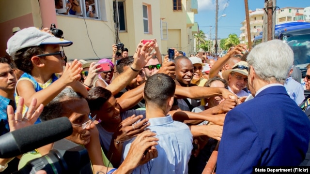 El secretario de Estado John Kerry saluda a cubanos frente a la Embajada de EE.UU. en La Habana, reabierta este viernes