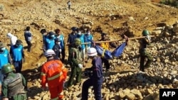Soldiers carry the bodies of miners killed by a landslide in a jade mining area in Hpakhant, in Myanmar's Kachin state on November 22, 2015. 