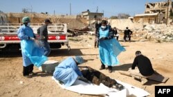 FILE - Members of the Libyan Red Crescent exhume unidentified bodies from a mass grave of people killed during fighting, in Benghazi, Libya, Feb. 23, 2017. A mass grave containing 36 unidentified bodies has just been discovered near Benghazi. 