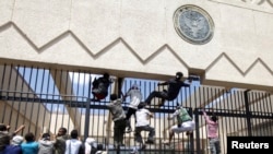 Manifestantes escalan una cerca en la embajada de EE.UU. en Saná, el 13 de septiembre, de 2012.