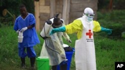 FILE - In this photo taken Sept. 9, 2018, a health worker sprays disinfectant on his colleague after working at an Ebola treatment center in Beni, DRC.
