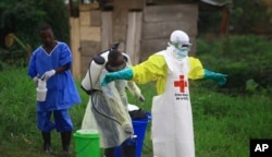 REPORT - In this photo taken September 9, 2018, a health worker sprays a disinfectant on his colleague after working in an Ebola treatment center in Beni, DRC.