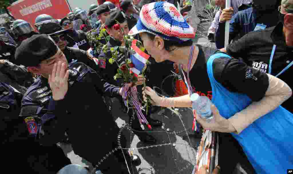 An anti-government protester gives a rose to Thai police officer during a rally in Bangkok, Nov. 25, 2013. 