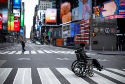 Un hombre en silla de ruedas cruza una séptima avenida casi vacía en Times Square en Manhattan durante el brote de coronavirus.