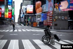 Un hombre en silla de ruedas cruza una séptima avenida casi vacía en Times Square en Manhattan durante el brote de coronavirus.