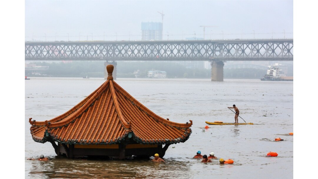 Warga berenang di Sungai Yangtze yang meluap hingga mencapai atap sebuah paviliun di Wuhan, provinsi Hubei tengah, China, 8 Juli 2020. (Foto oleh STR / AFP)