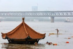 Warga berenang di Sungai Yangtze yang meluap hingga mencapai atap sebuah paviliun di Wuhan, provinsi Hubei tengah, China, 8 Juli 2020. (Foto oleh STR / AFP)