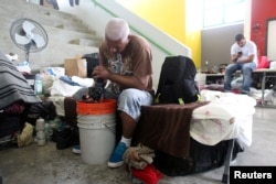 A man does his laundry while sitting on a cot at a school turned shelter after he lost his home during Hurricane Maria in September as former U.S. President Bill Clinton visits Canovanas, Puerto Rico, Nov. 20, 2017.