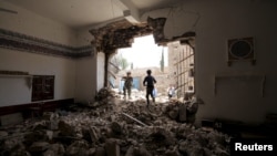 People enter a damaged mosque from a hole in its wall at the site of a car bomb attack in Yemen's capital, Sana'a, June 18, 2015.