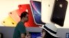 A customer looks at her iPhone in a store of U.S. tech company Apple in Beijing, May 10, 2019. China says it is imposing tariffs on $60 billion worth of imports from the United States.
