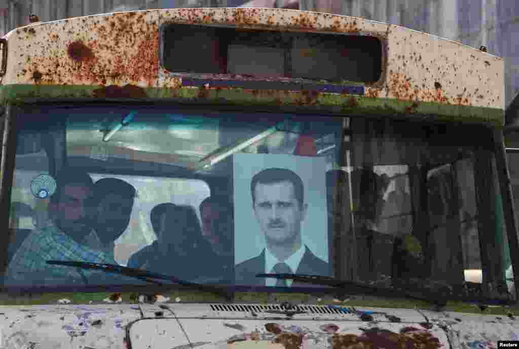 People ride on a bus as they head to a polling station to cast their vote, during the presidential elections, in Damascus, Syria.