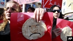 Women hold signs, with bread taped on them, demonstrate against the government in Amman, Jordan, 14 Jan 2011