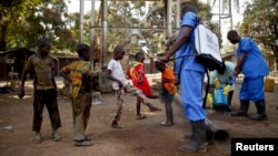 Children come forward to get their feet disinfected after Red Cross workers explained that they were spraying bleach, and weren't spraying the village with the Ebola virus, in Guinea's Forecariah district, Jan. 30, 2015.