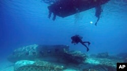 In this photo taken on Friday, Nov. 6, 2015, diver Hiroaki Ueda submerges below his boat as they explore a wrecked DC3 aircraft in the Majuro Atoll lagoon at the Marshall Islands.