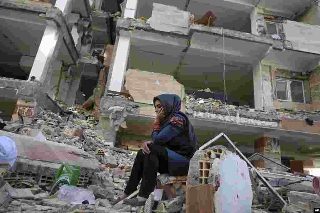 An earthquake survivor sits on debris in front of her house, which was built under the Mehr state-owned program, in Sarpol-e-Zahab in western Iran.&nbsp;