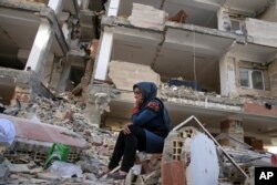 An earthquake survivor sits on debris in front of his house in a compound, which was built under the Mehr state-owned program, in Sarpol-e-Zahab in western Iran, Nov. 14, 2017.