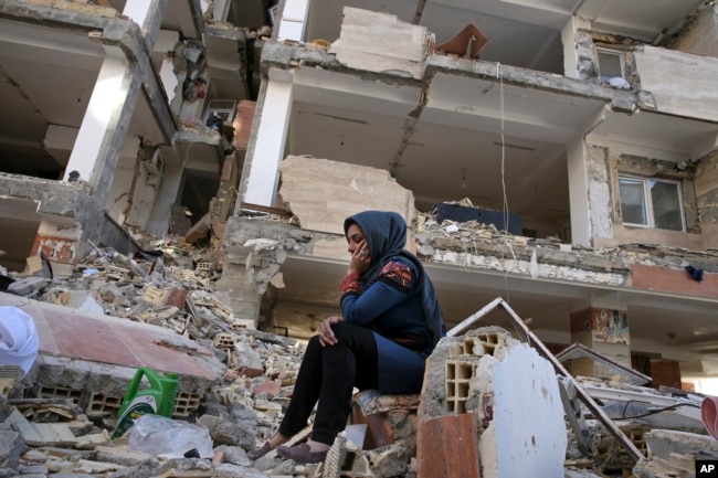 An earthquake survivor sits on debris in front of his house in a compound, which was built under the Mehr state-owned program, in Sarpol-e-Zahab in western Iran, Nov. 14, 2017.