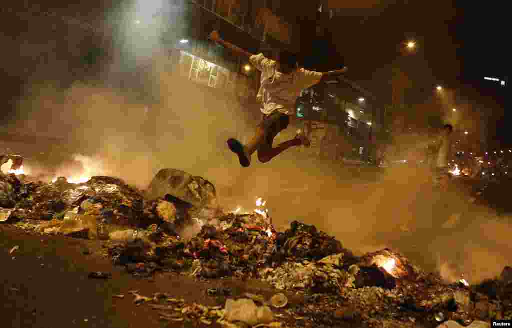 A boy jumps over a barricade of burning garbage that supporters of opposition leader Henrique Capriles used to block a street, as they demonstrated for a recount of the votes in Sunday&#39;s election, in Caracas, April 15, 2013.&nbsp;