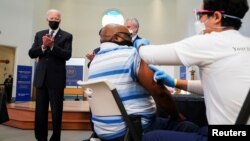 U.S. President Joe Biden applauds a man as he receives a vaccine at the coronavirus disease (COVID-19) vaccination site at Virginia Theological Seminary in Alexandria, Virginia, U.S., April 6, 2021. REUTERS/Kevin Lamarque