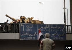 An anti-government protester looks towards an Egyptian tank on a bridge near Tahrir, or Liberation square in Cairo, Egypt, Thursday, Feb. 3, 2011. (AFP PHOTO)