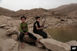 FILE - A 17-year-old boy holds his weapon in High dam in Marib, Yemen, July 30, 2018.