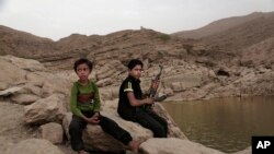 FILE - A 17-year-old boy holds his weapon in High dam in Marib, Yemen, July 30, 2018. Experts say child soldiers are “the firewood” in the inferno of Yemen’s civil war, trained to fight, kill and die on the front lines.