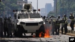 A Molotov cocktail burns next to Venezuelan Bolivarian National Police officers during a protest in Caracas, April 8, 2017.