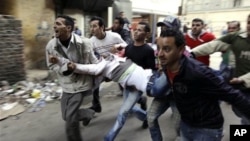 Egyptians carry an injured protester during clashes with anti-riot police in Cairo, Egypt, Saturday, Jan. 29, 2011.