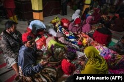 Warga berkumpul di posko pengungsian di Desa Sumber Wuluh di Lumajang pada 5 Desember 2021, pasca erupsi Gunung Semeru yang menewaskan sedikitnya 14 orang. Foto: AFP/Juni Kriswanto)