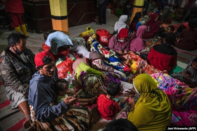 Warga berkumpul di posko pengungsian di Desa Sumber Wuluh di Lumajang pada 5 Desember 2021, pasca erupsi Gunung Semeru yang menewaskan sedikitnya 14 orang. Foto: AFP/Juni Kriswanto)