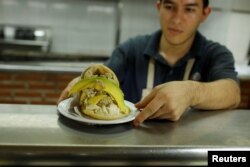 A worker serves an arepa stuffed with cheese, hen salad and avocado at a restaurant in Caracas, Venezuela, Dec. 19, 2017.