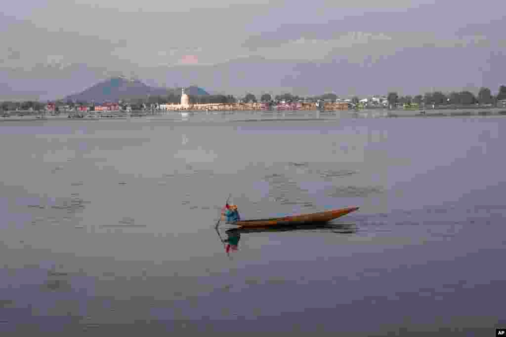 یک زن کشمیری در ایالت سرینگر هند از روی دریاچه برای دام های خود علف جمع می&zwnj;کند.&nbsp;