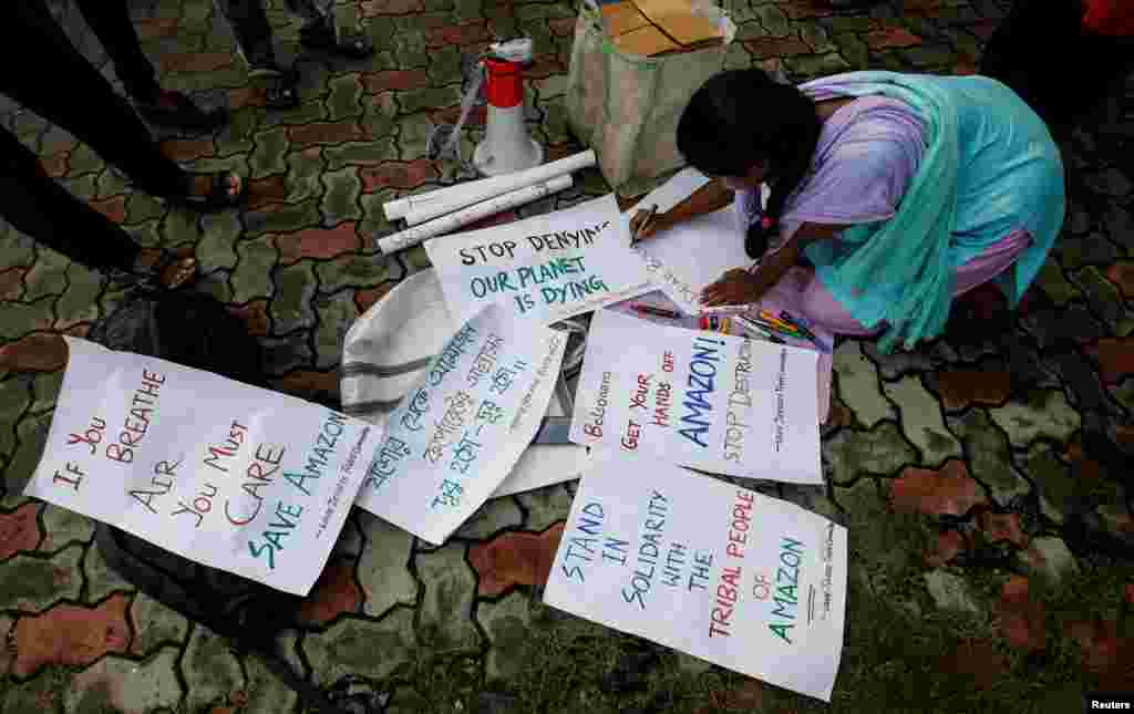 A student writes placards before a protest march demanding protection for the Amazon rainforest near the consulate of Brazil in Kolkata, India.