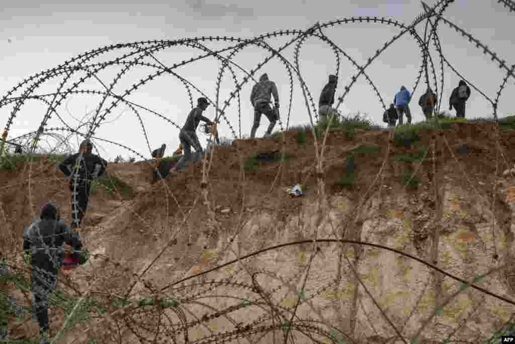 Palestinians go through a wire fence into Israel as they attempt to cross to reach their workplaces close to the Israeli checkpoint of Mitar, near Hebron in the occupied West Bank, during a nationwide lockdown enforced by Israeli officials.