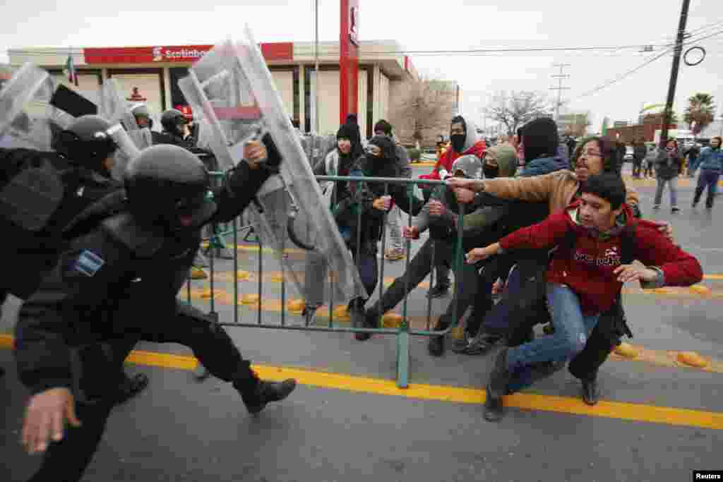 Demonstrators pull a barrier as federal policemen try to stop them during a protest against the visit of Mexico&#39;s President Enrique Pena Nieto to the city, in Ciudad Juarez, Jan. 14, 2015.