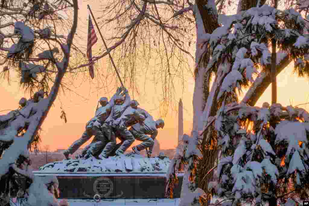 The snow-covered U.S. Marine Corp Memorial is framed through the trees at sunrise in Arlington, Virginia, after a winter storm blanketed the Washington D.C. area with several inches of snow Thursday.