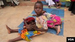 A girl rescued from the Sambisa forest cradles another girl in her lap at a displaced persons camp in Malkohi, Nigeria on May 5, 2015. (VOA / Chris Stein)