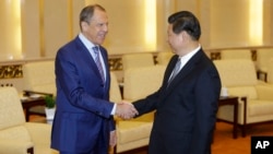 Russian Foreign Minister Sergei Lavrov (L), shakes hands with China's President Xi Jinping during a meeting at the Great Hall of the People in Beijing, Tuesday, April 15, 2014.