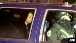 FILE - U.S.-Taliban fighter John Walker Lindh, 2nd left, rides in the back seat with security officers as they arrive at the Alexandria Detention Center in Alexandria, Virginia, Jan. 23, 2002. 