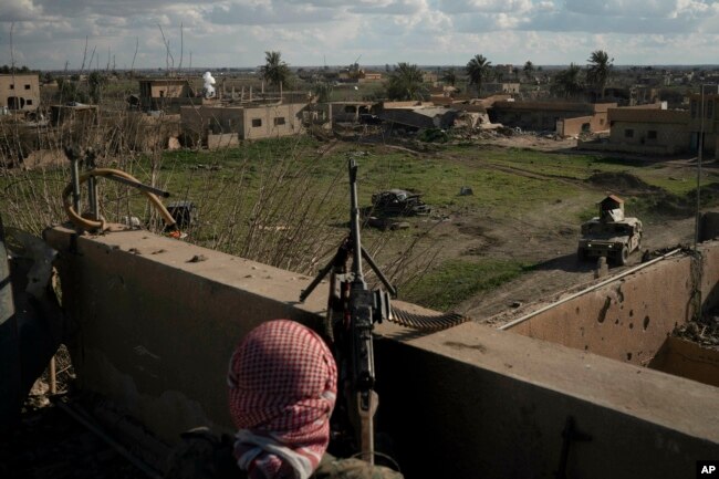 A U.S.-backed Syrian Democratic Forces fighter stands atop a building used as a temporary base near the last land still held by Islamic State militants in Baghouz, Syria, Feb. 18, 2019.