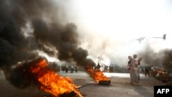 A Sudanese protester walks past burning tires as military forces tried to disperse the sit-in outside Khartoum's army headquarters on June 3, 2019.