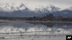 FILE- The Chugach Mountains and the buildings of downtown Anchorage, Alaska, are reflected in the still waters of Cook Inlet, Feb. 12, 2016.