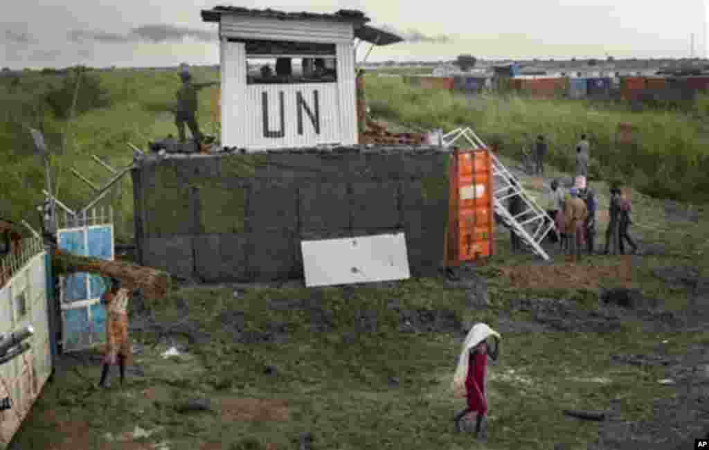 Les déplacés sud-soudanaises quittent le camp pendant la journée pour ramasser du bois et d&#39;autres produits, à côté des casques bleus en provenance de Mongolie qui gardaient la porte, dans un camp de fortune pour personnes déplacées situé dans le village de Bentiu, au Soudan du Sud. 