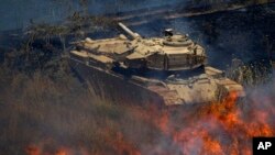 An old tank is surrounded by fire following explosions of mortar shells from Syria on the Israeli controlled Golan Heights, July 16, 2013. 