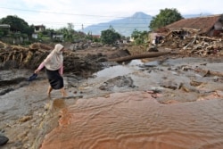 Seorang perempuan berjalan melalui kawasan yang rusak akibat banjir bandang di desa Bulukerto, Batu, Jawa Timur, Jumat, 5 November 2021.