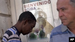 A poster showing Pope Benedict XVI, the Virgin of Charity of Cobre, Cuba's patron, is displayed on a window in Santiago de Cuba, Cuba, Sunday, March. 25, 2012. 