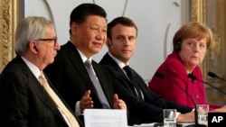 French President Emmanuel Macron, second right, Chinese President Xi Jinping, German Chancellor Angela Merkel and European Commission President Jean-Claude Juncker, left, hold a press conference at the Elysee presidential palace in Paris.