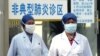 FILE PHOTO - Chinese health workers wear protective garments and masks walk in front of the clinic marked as "atypical pneumonia clinic zone", Beijing, China. 