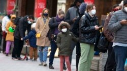 FILE - People wait in line outside a COVID-19 walk-in testing site, Dec. 5, 2021, in Cambridge, Mass. The fast-moving omicron variant may cause less severe disease on average, but COVID-19 deaths in the U.S. are climbing.