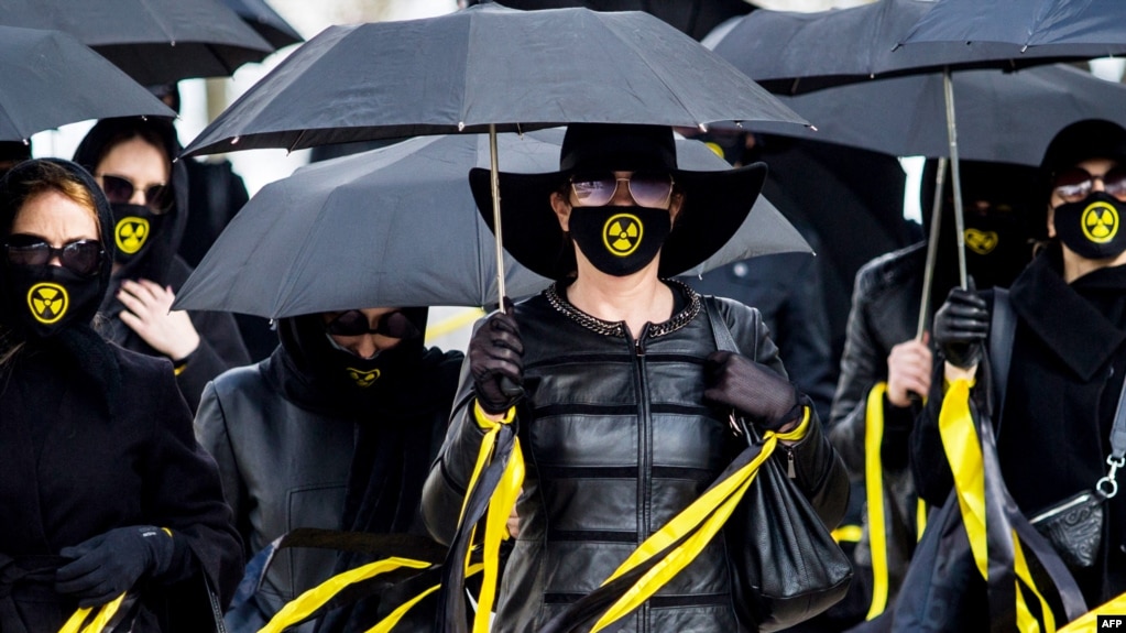身穿黑衣戴着核辐射图样口罩的人们在明斯克纪念35年前在切尔诺贝利核事故中的死难者。（2021年4月26日）(photo:VOA)